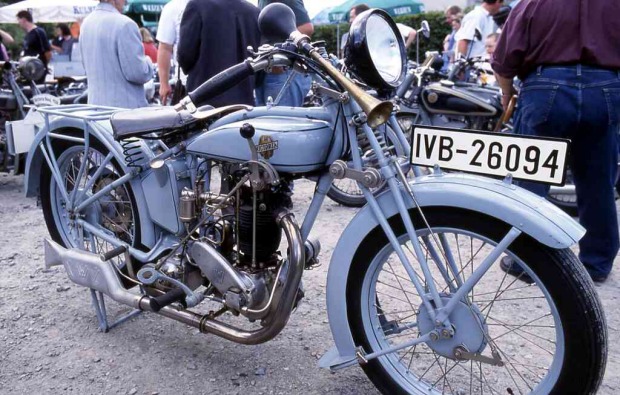 Graublaues Motorrad mit großem Scheinwerfer und Ballonhupe.