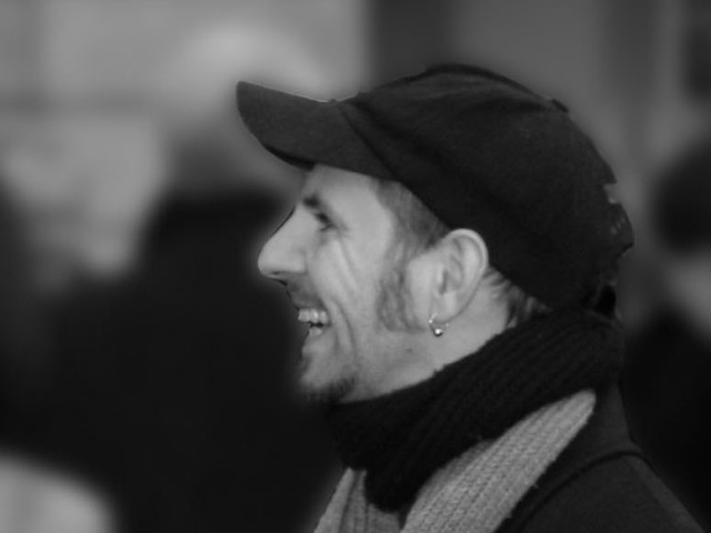 Ronny Schmid mit schwarzer Baseball–Kappe in Profil, er lacht.