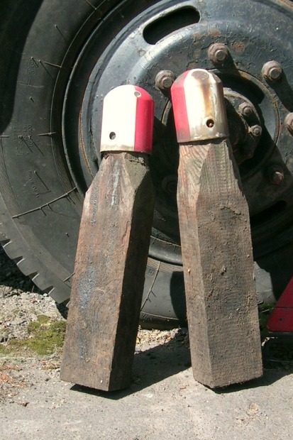 Foto: zwei Holzpflöcke mit rot–weißen Blechkappen.