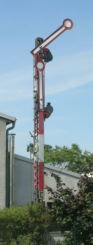 Rot–weiß–grau lackiertes Signal mit zwei Signalflügeln und Gittermast.