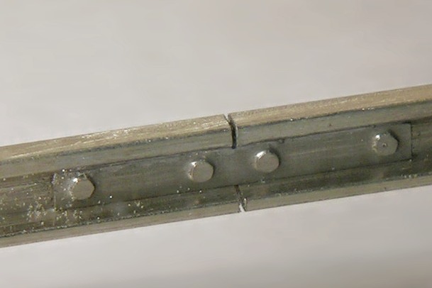 Großaufnahme einer geätzten Schienenlasche mit vier Sechskant–Imitationen.