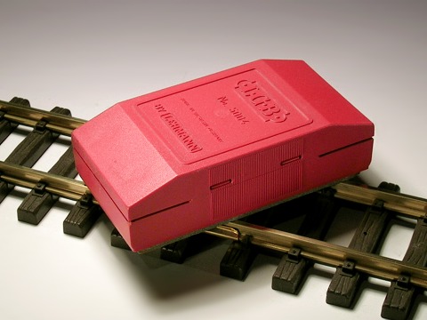 Foto: Handschleifer mit rotem Kunststoff–Gehäuse auf Schienen.