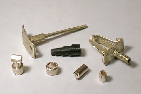 Messingteile für eine Pufferkonstruktion: Korb, Schaft mit Teller, Wickelfeder und hintere Aufname für den Balancierhebel.