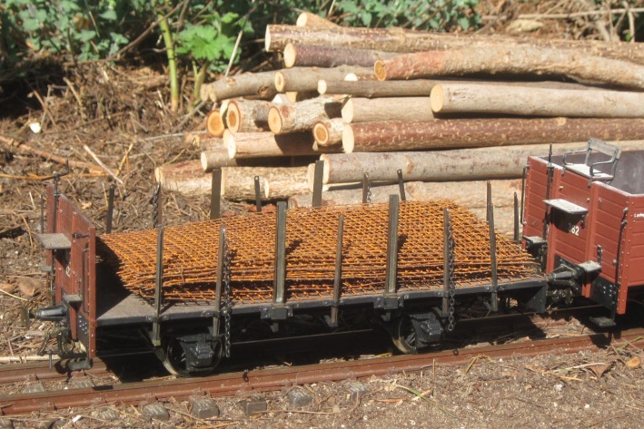 Ein zweiachsiger Rungenwagen mit rostigen Baustahlmatten als Ladegut.