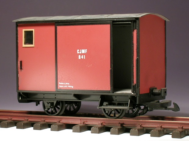 Modellfoto: kleiner, rotbrauner, geschlossener Güterwagen mit einer großen Schiebetür und einem Fensterchen in der Seitenwand.