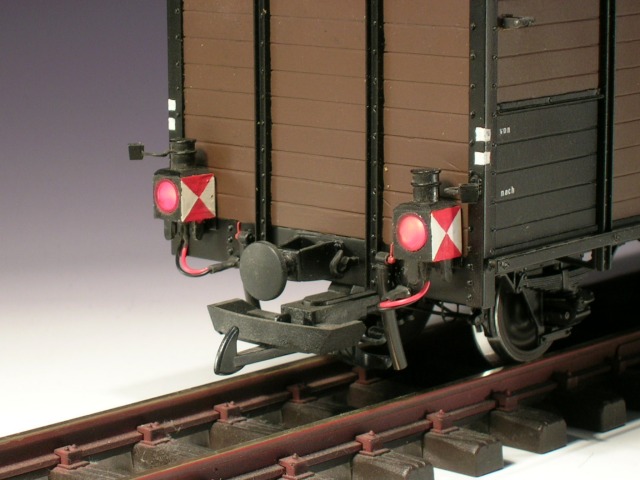 Modellfoto: Beleuchtete Zugschluss–Laternen an einem gedeckten Güterwagen.