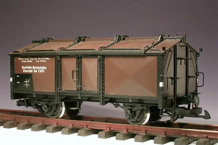 Brauner Güterwagen mit flachem Giebeldach und sechs Dachklappen.