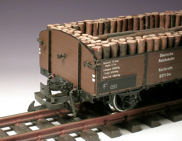 Offener Hochbord–Güterwagen, abgerundete Stirnwände, eine Ladung aus Grubenholz.