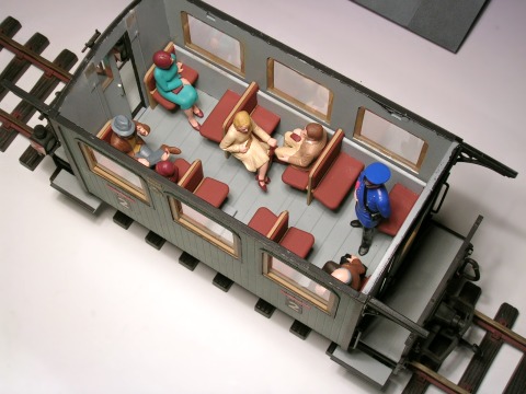 Sitzende Reisende im Reisezugwagen mit 2 × 3 gegenüber liegenden Sitzbänken.
