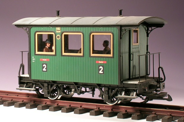 Modellfoto: grüner Personenwagen zweiter Klasse mit zwei Bühnen und holzfarbenen Fensterrahmen.