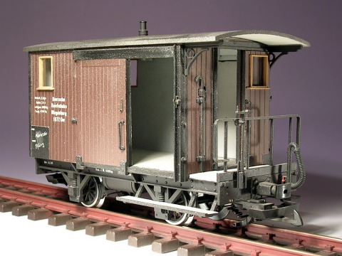 Modellfoto: Brauner, gedeckter Güterwagen mit Bremserbühne schräg von vorne gesehen.